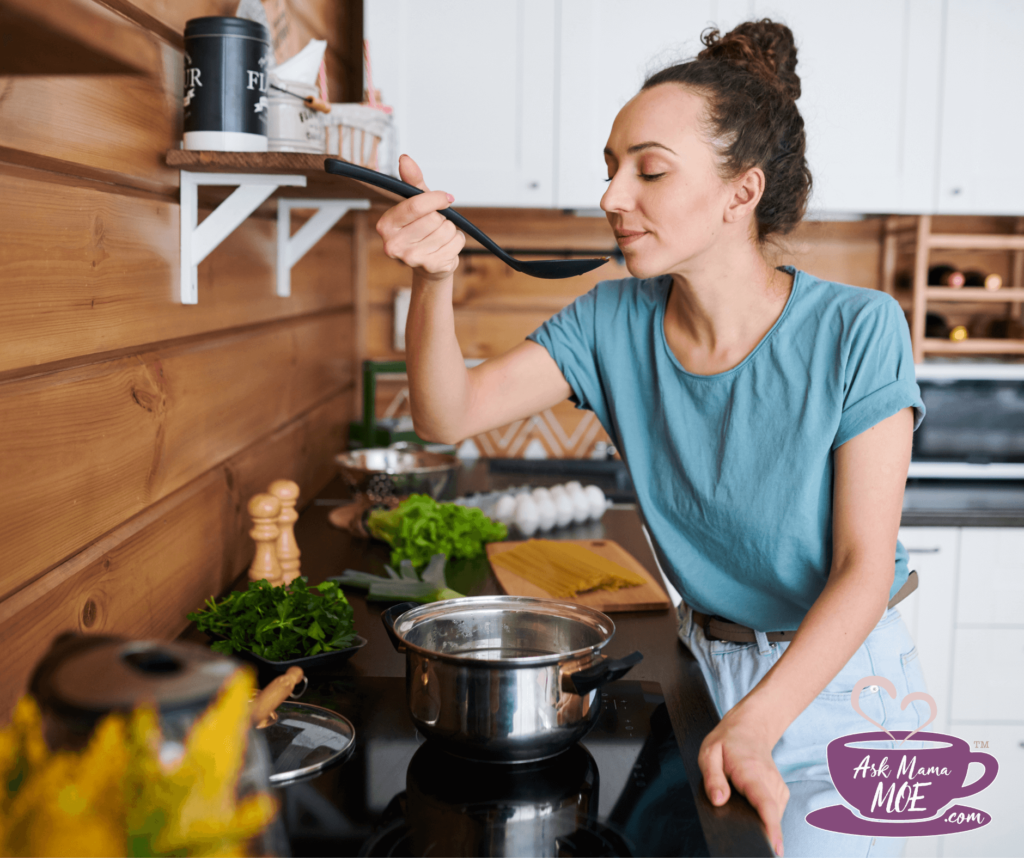 A woman with a high bun and wearing a mint green shirt smelling her cooking