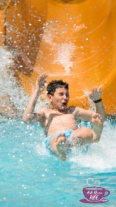 A young brunette boy sliding down an orange water slide