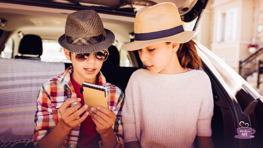 A young boy and girl looking at a small notepad in a car