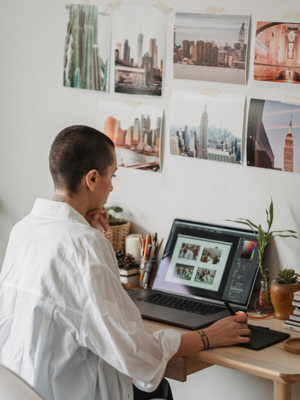 A woman wearing a white collared shirt, looking at photos on her black laptop