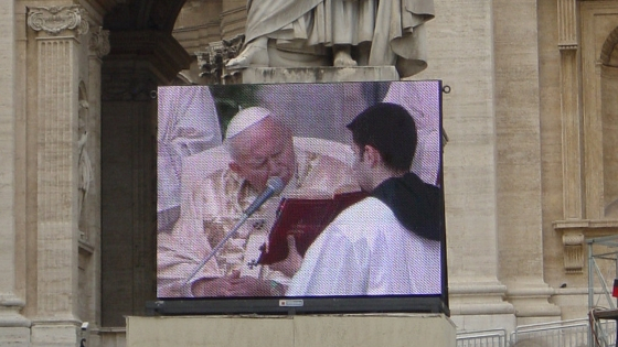 The pope on a large screen, reading from the Bible.