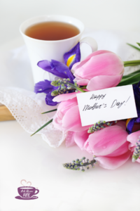 A bouquet of flowers laying on a table with a card that says, "Happy Mother's Day"