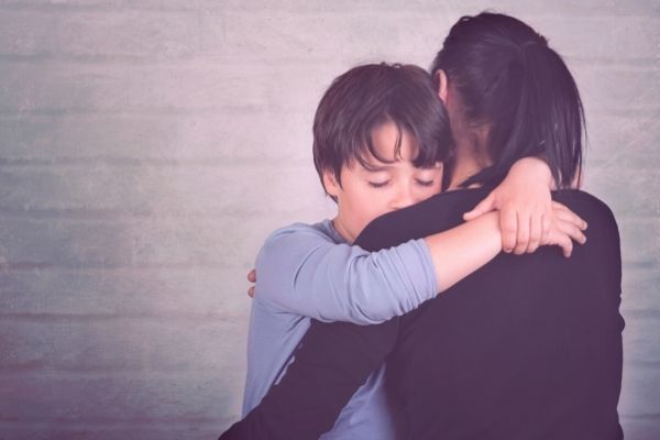 Young boy hugging parent